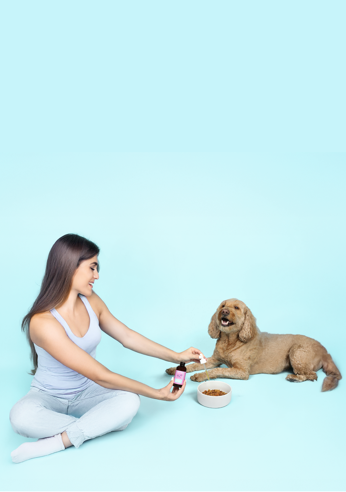 Woman sitting on the floor with a dog on a light blue background