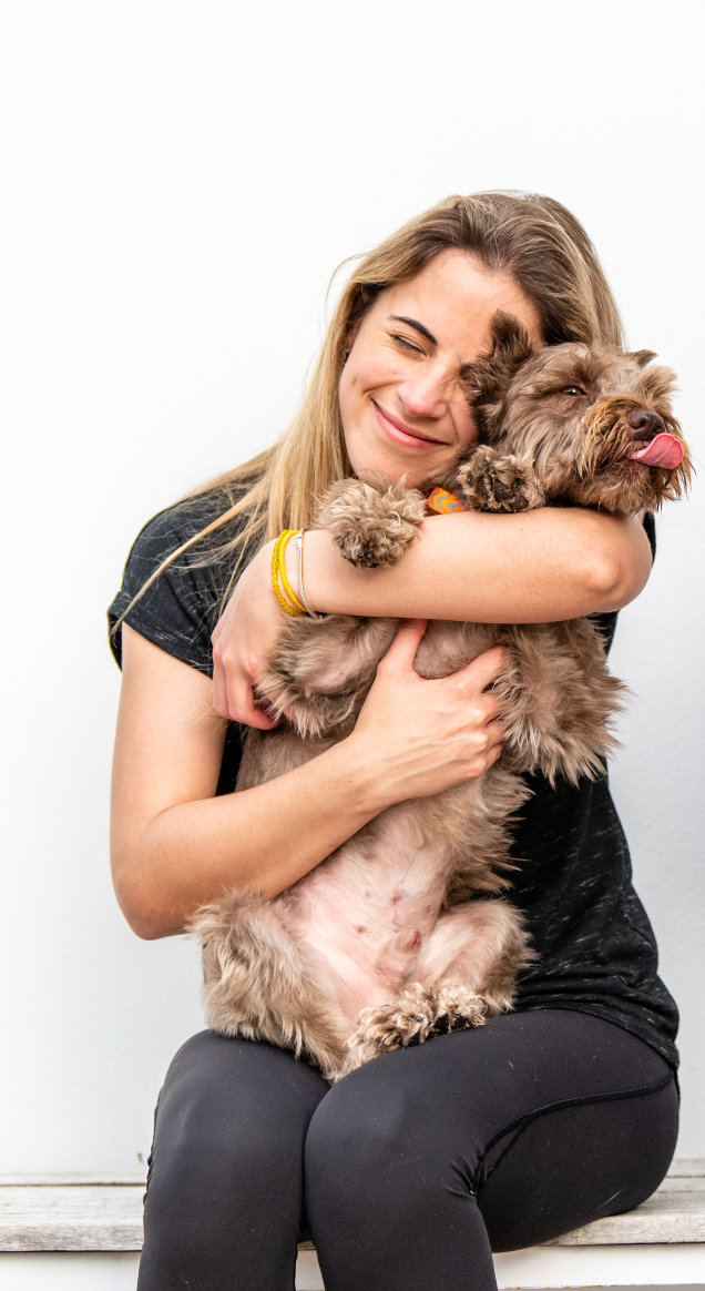 Woman hugging a small brown dog on a white background